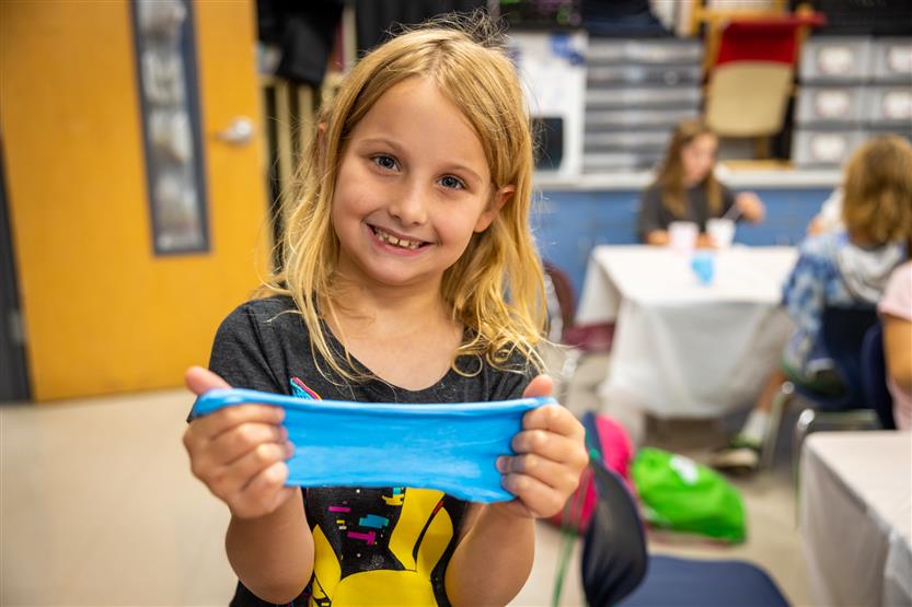 A girl with blonde hair holds slime